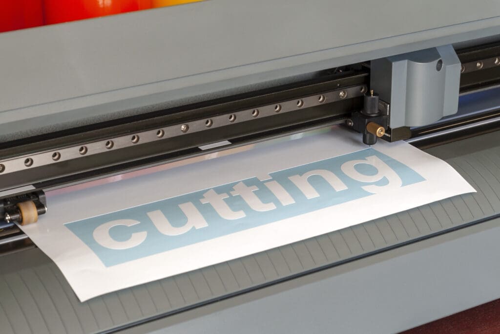 An image of a vinyl cutter in operation, with a sharp blade precisely cutting through a sheet of vinyl material.